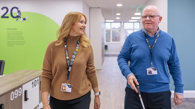Two Guide Dogs employees walk down an office corridor