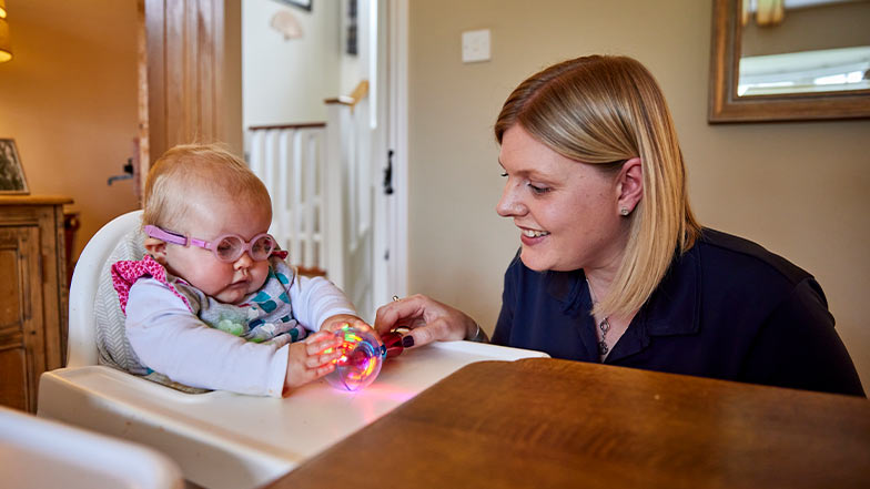 A Habilitation Specialist smiles as she plays with toys with a young service user.