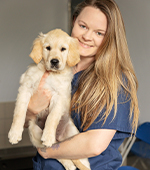 Becky Hunt, Breeding Programme Data Manager, smiles while holding a guide dog puppy.