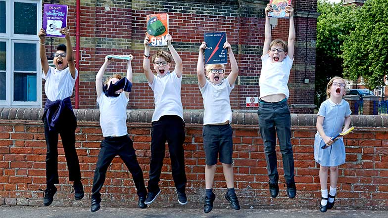 Six children jump holding their CustomEyes books above their heads