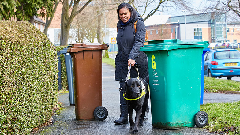 Guide dog owner tries to navigate around bins on the pavement with guide dog