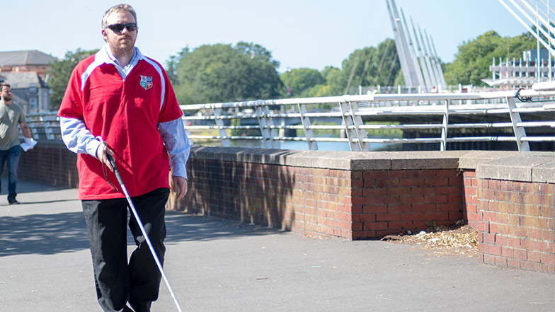 Man using cane walks outside alone