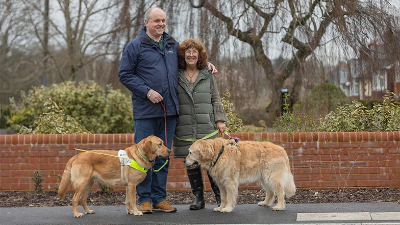 A guide dog owner, and his wife, stand with a retired and current guide dog as they set out on a walk.