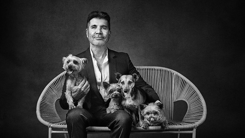 Black and white picture of Simon Cowell with his four small dogs Squiddly, Diddly, Freddy and Daisy