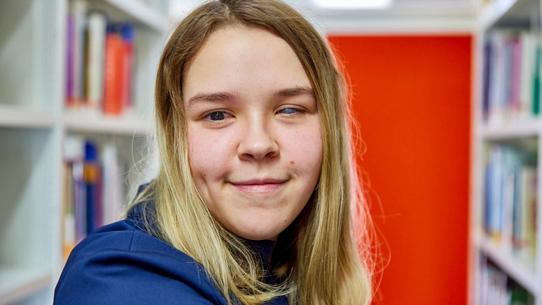 Headshot of a smiling young woman in a library