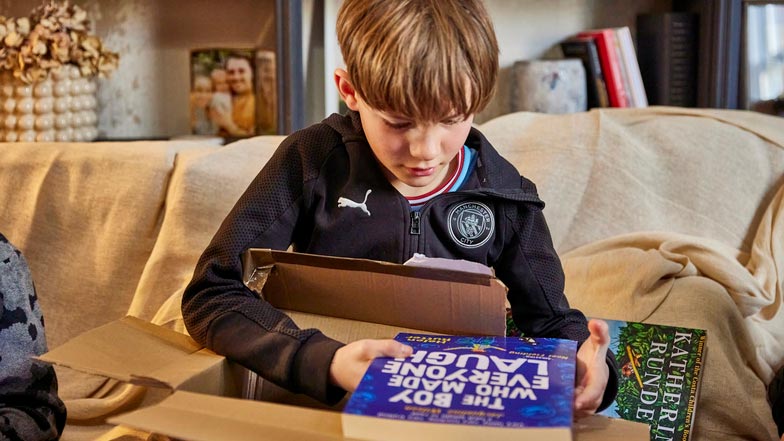 Ralph, a young service user, reads a book with enlarged font.