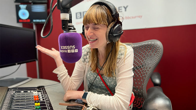 Fern who has a vision impairment is the in BBC radio studio mid conversation in front of a mic. 