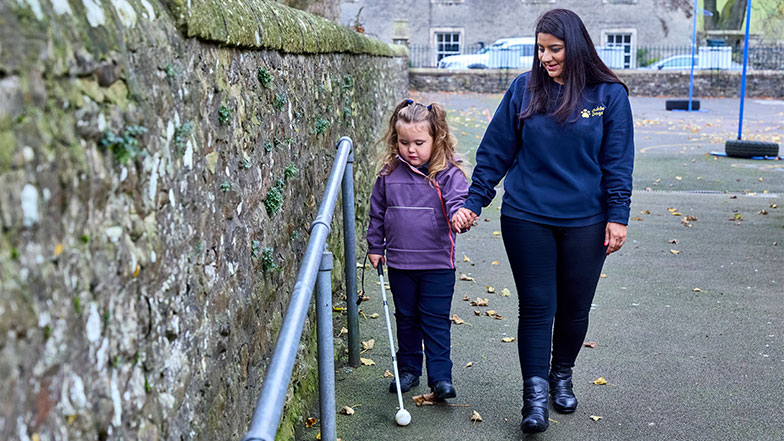Sunita a habilitation specialist with a vision impairment, guiding four year old Mabel on how to use her cane.