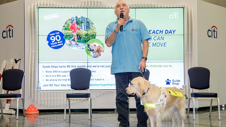 Guide dog owner stands up with his guide dog to present to staff at Citi