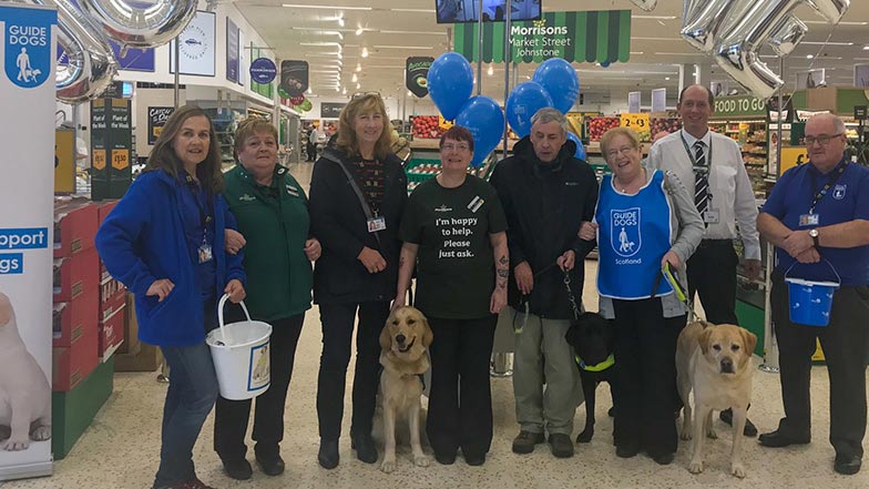 Morrisons Johnstone staff stand with collection buckets beside Guide Dogs volunteers in store