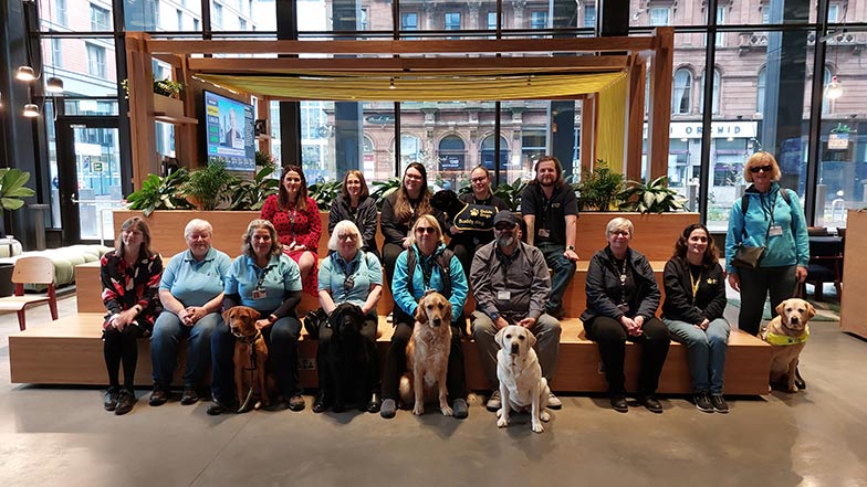 JP Morgan staff sitting in large office atrium with Guide Dogs staff and dogs
