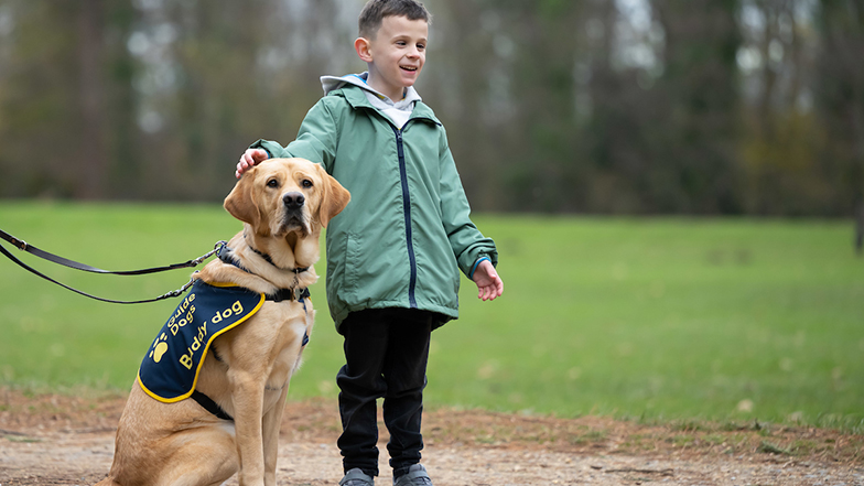 Young boy Alfie in the park stood next to yellow Labrador buddy dog Cooper