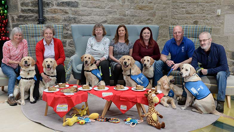 People's Postcode Lottery funded puppies all sit round with their puppy raisers to celebrate their first birthday