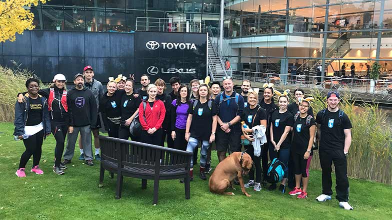 Toyota staff stand in a group outside the Toyota office before doing a marathon walk