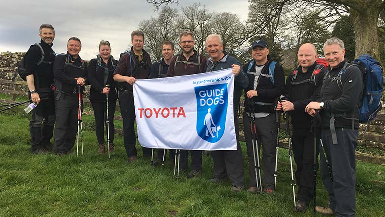 Toyota Directors stand with a Toyota banner before doing a walking challenge