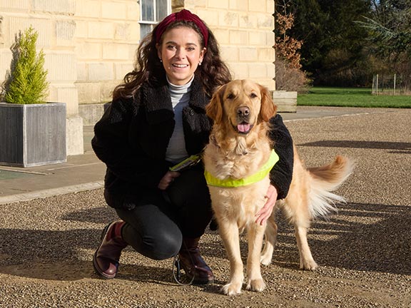 Guide dog owner Taylor crouching next to her guide dog Jilly