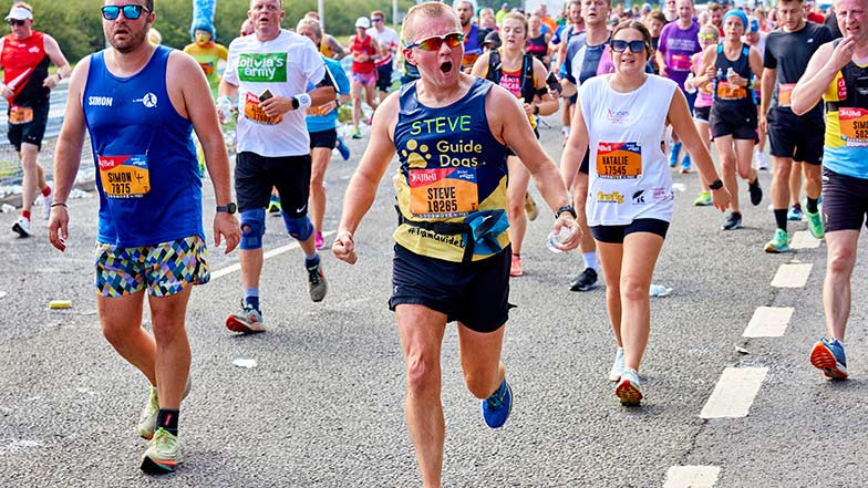 Runner wearing a Guide Dogs t-shirt cheering as they run