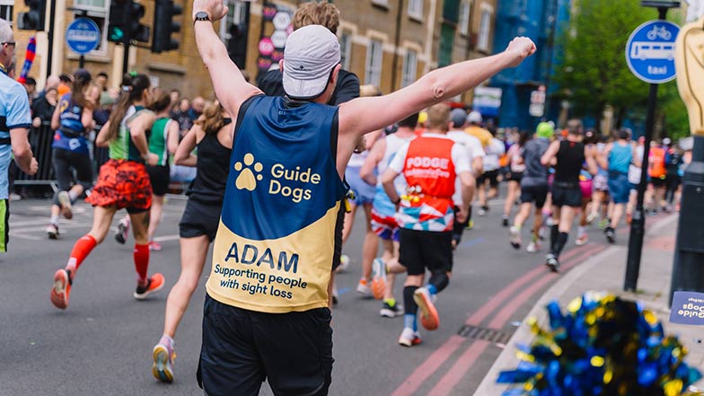 Runner wearing a Guide Dogs t-shirt and celebrating  as they run