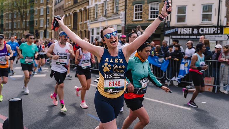 Runner in a Guide Dogs vest at the TCS London Marathon cheering to camera