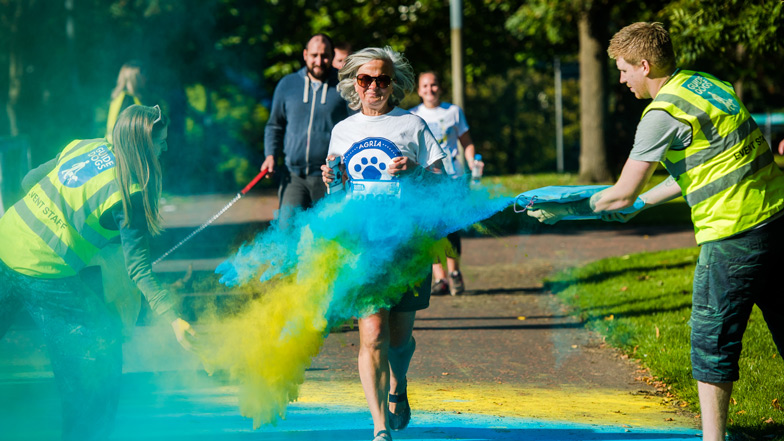 Guide Dogs volunteers throwing colourful paint as runners cross the finishing line