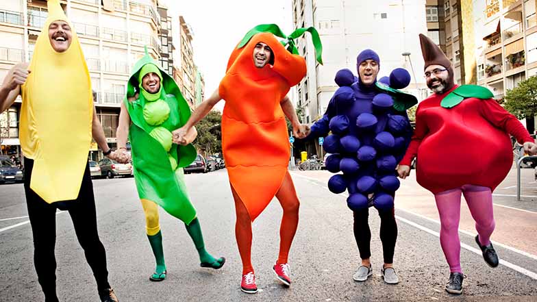 A group of men are dressed in fruit and vegetable costumes and smiling. 