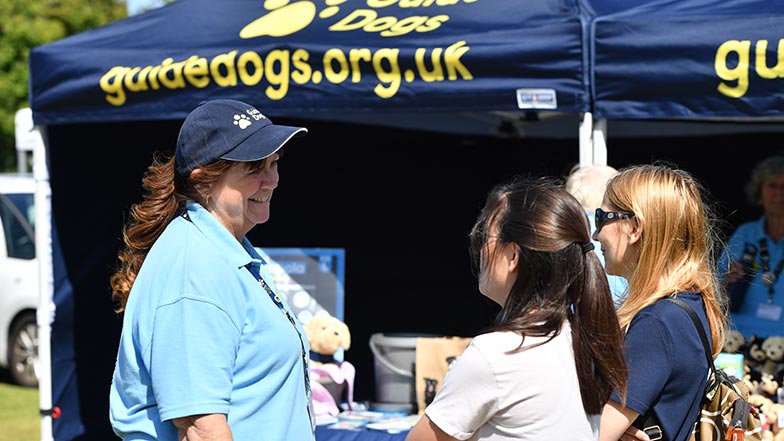 Guide Dogs volunteer talking to two people.