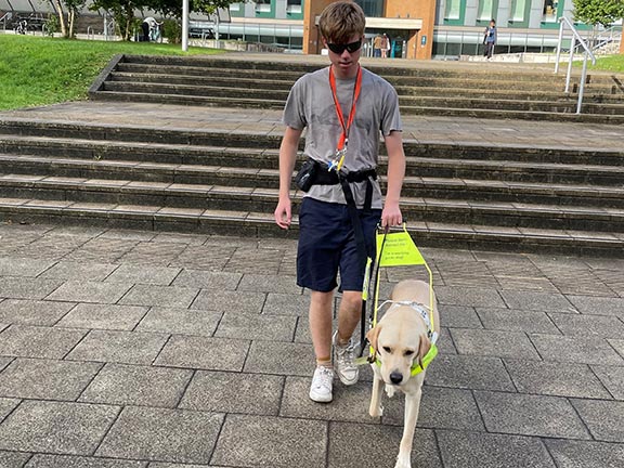 Freddy with his guide dog Tyson walking on university campus