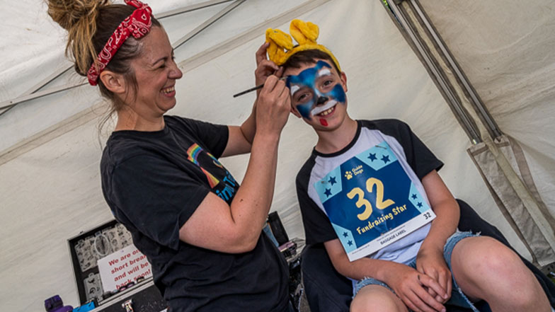 A young boy getting his face painted at the Guide Dogs Run