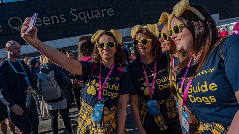 A group of people wearing Guide Dogs t-shirts and dog ears at a Kiltwalk event
