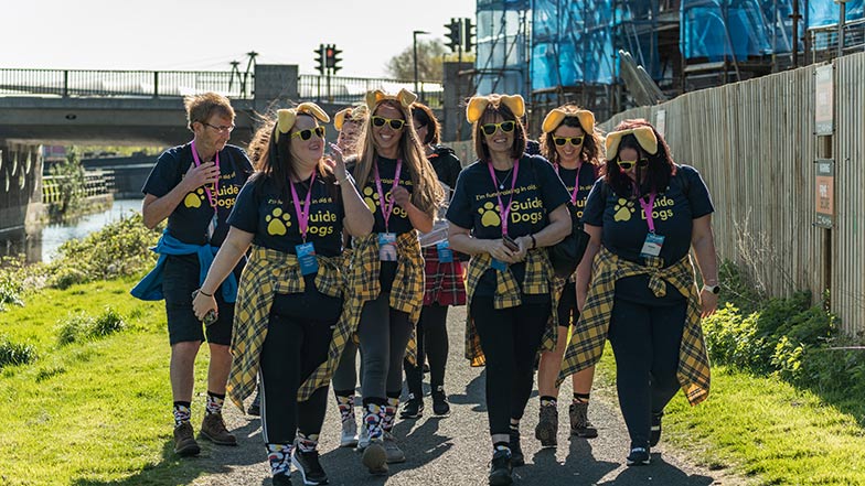 A group of people wearing Guide Dogs t-shirts and dog ears at a Kiltwalk event