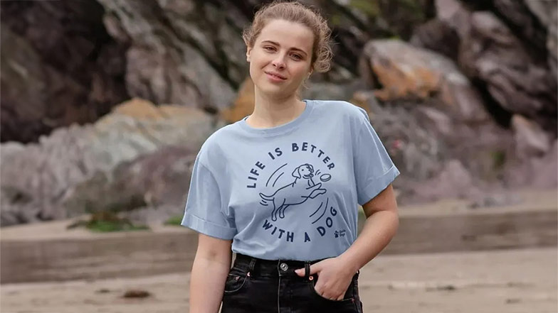 A woman wearing a blue t-shirt with the words 'life is better with a dog' from the Guide Dogs Teemill collection