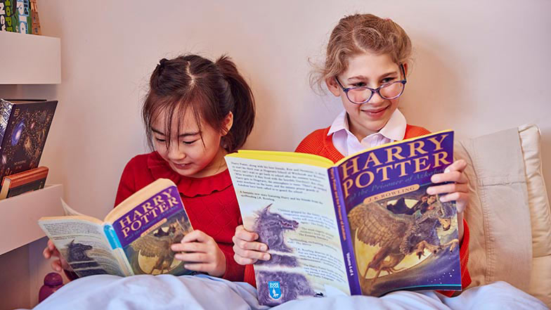 Josie and her friend Flora sitting reading with a book from CustomEyes Books