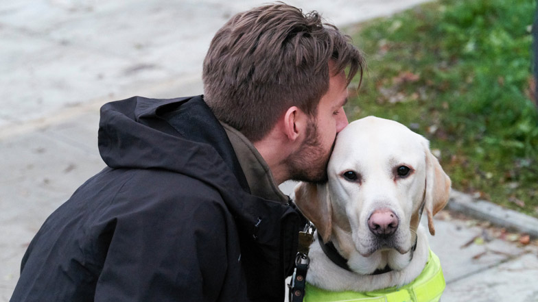Guide dog owner embracing his dog