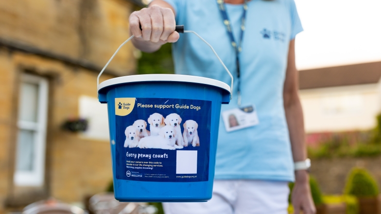 A Guide Dogs volunteer holding a collection bucket
