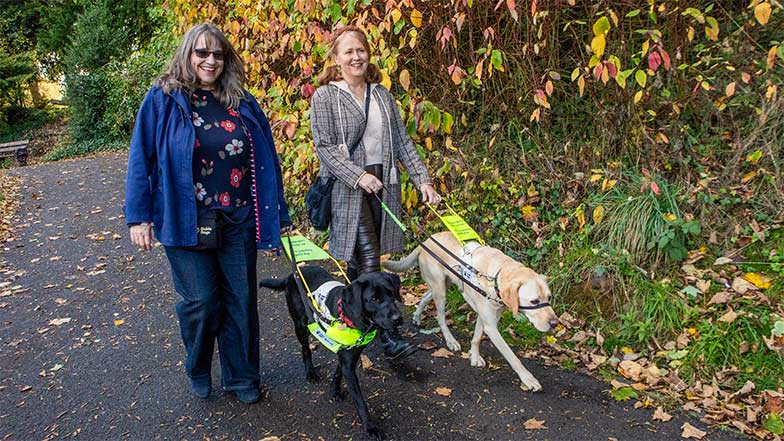 Guide dog owners Lesley and Heather walking with their guide dogs