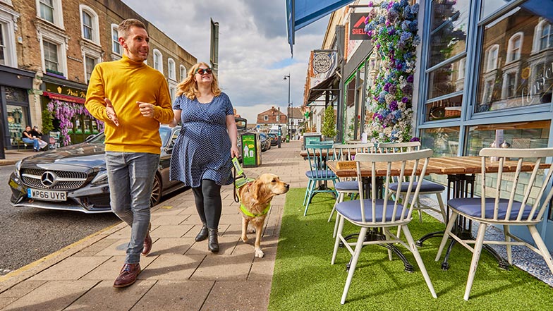 A man guiding a guide dog owner into a cafe