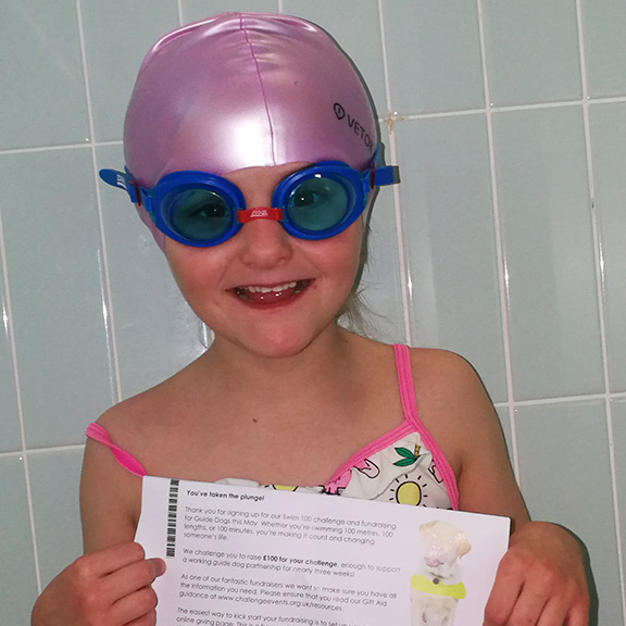 Zannah in her swimming hat with Swim 100 certificate