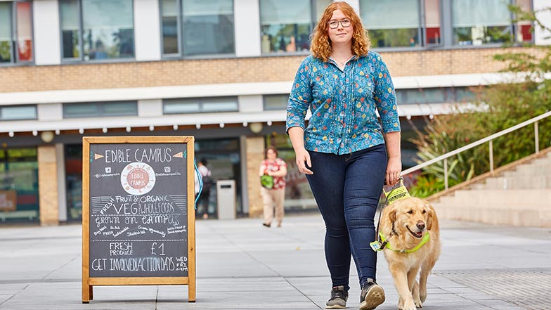 Ella and guide dog Katie walking together on university campus