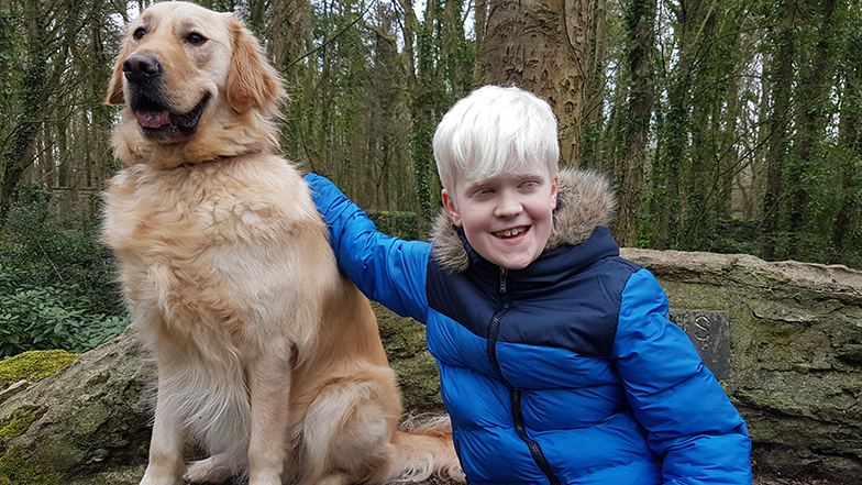 Ellis patting his buddy dog, Ralph, in a forest