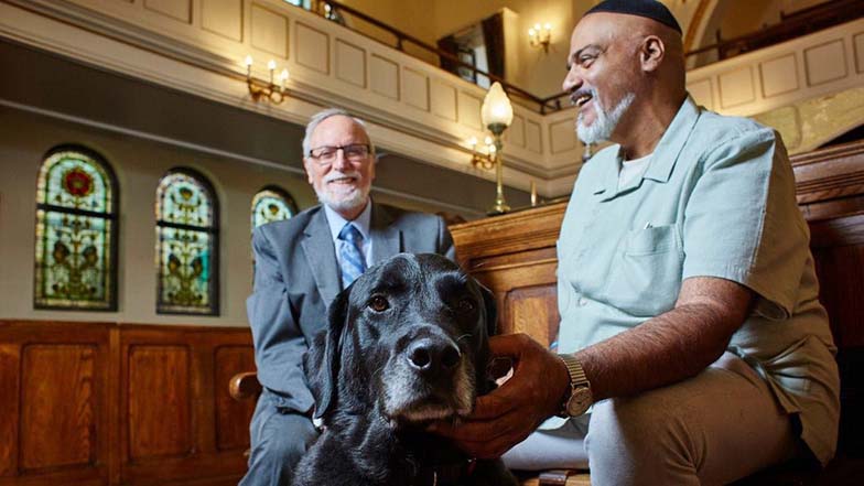 David sitting in the synagogue with the rabbi and his guide dog scooby 