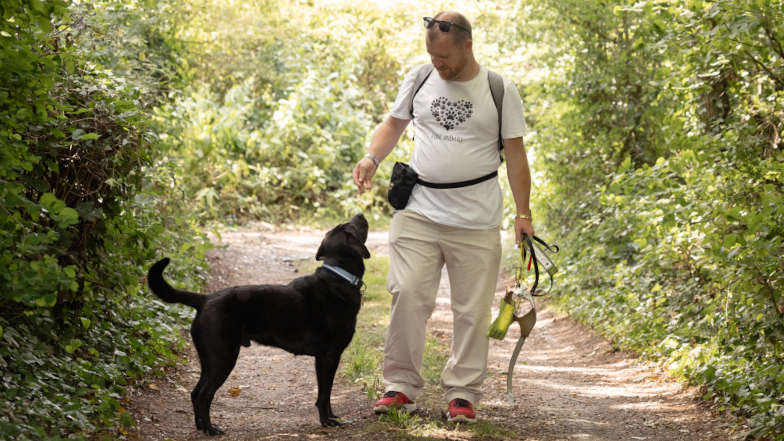 Guide dog owner James and guide dog Comet off harness walking in a wood