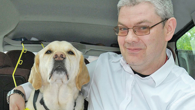 Guide dog owner and his guide dog sitting in a car