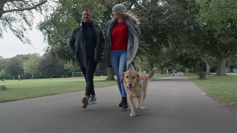 Guide dog owner Stacey walking with a friend in a park