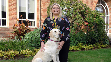 Smiling guide dog owner sitting with her guide dog