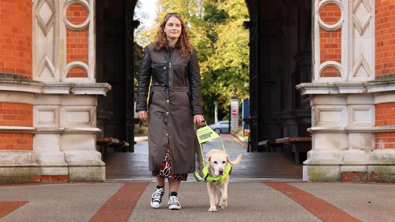 Guide dog owner Anica with Labrador  guide dog Lassie in harness walkiing through her university campus
