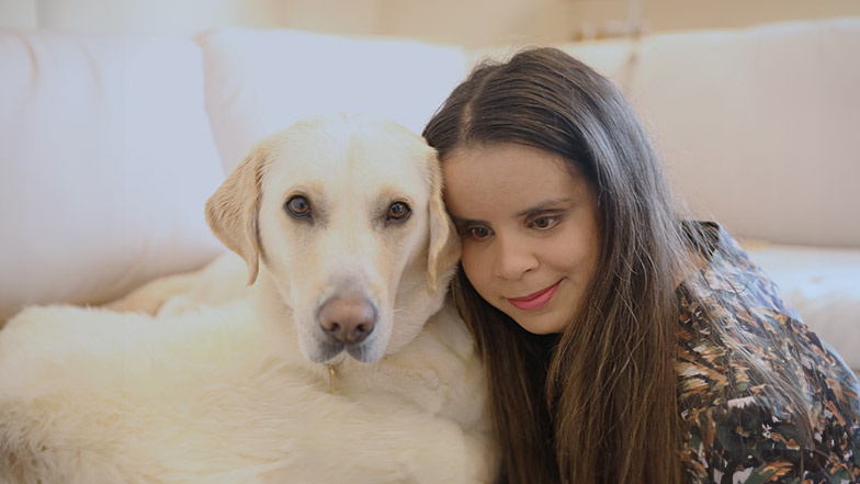 Guide dog owner Hannah with guide dog Wendy sitting in her living room.