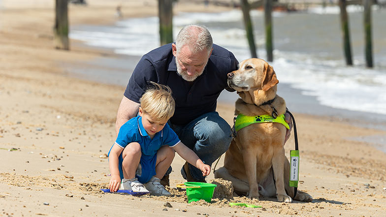 Simon and his grandson playing at the beach with Mayne at their side.