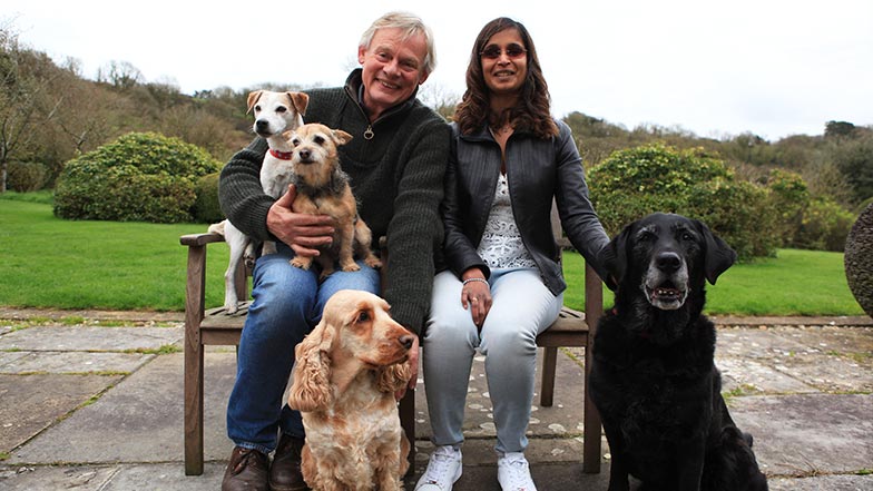 Jaina and Martin sit on a bench with Martin's dogs, including Laura