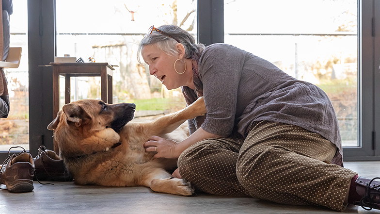 A guide dog owner sitting on the floor stroking their guide dog