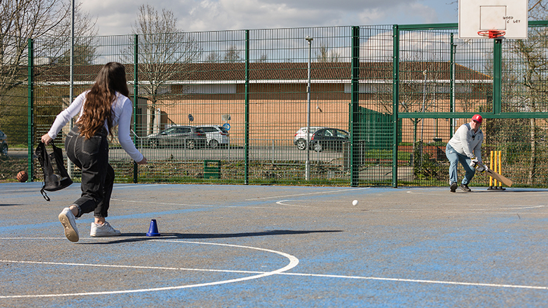 Two people playing blind cricket on an astroturf pitch